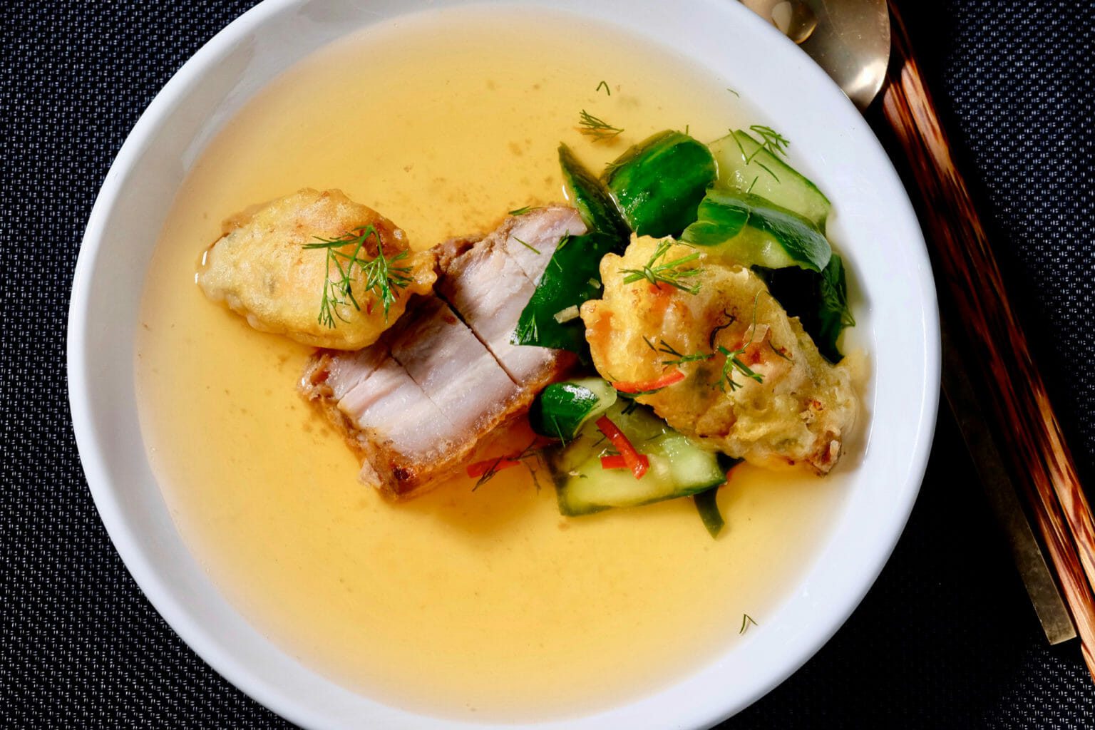 Kimchi consommé (clear soup) with crispy pork belly and tempura mussels