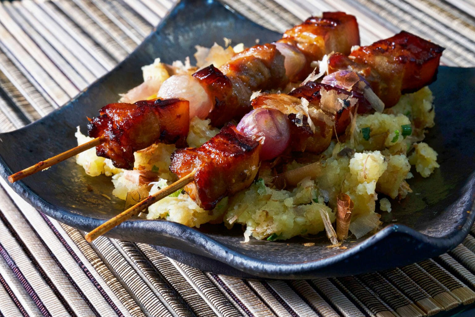 Marinated pork belly skewers on an Asian potato salad delectabilia